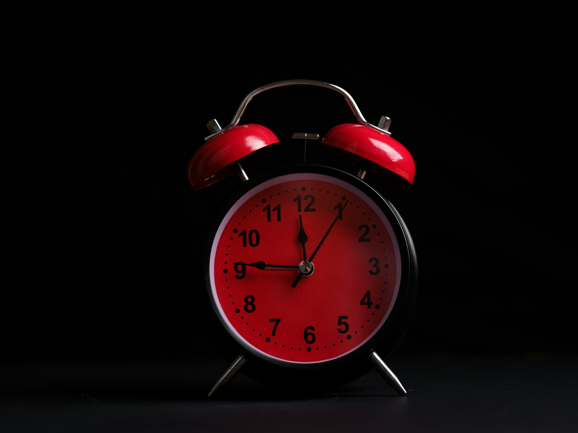 a red and black alarm clock on a black background